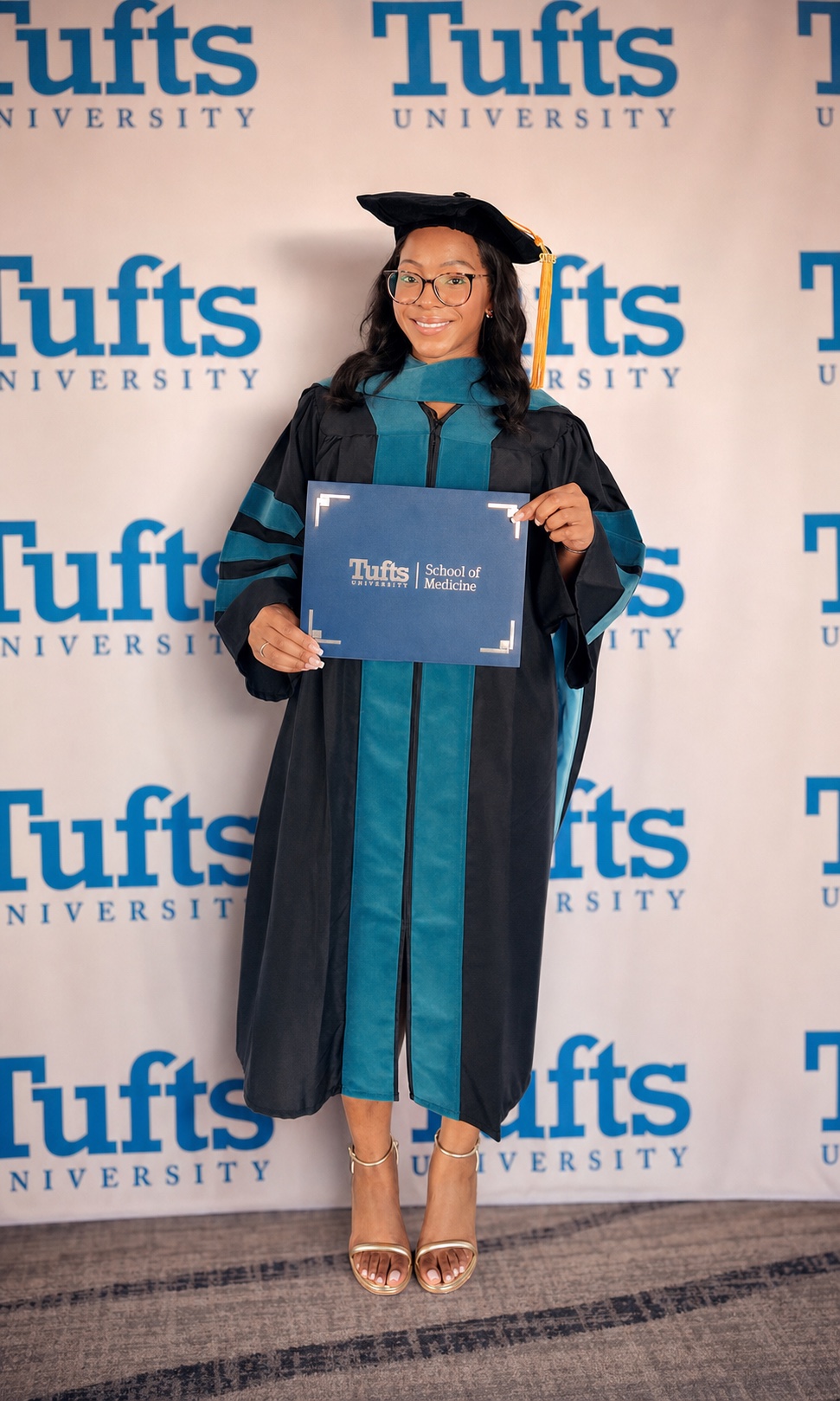 Dr. Dess in her doctoral regalia holding her Tufts University School of Medicine diploma